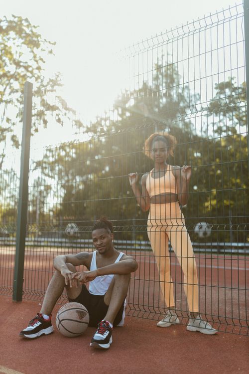 Free Two young adults enjoy leisure time at an outdoor basketball court with a sunny backdrop. Stock Photo
