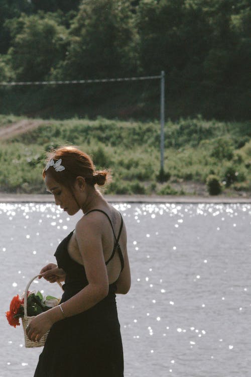 Woman in Black Dress Holding a Basket of Flowers 