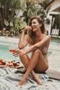 Woman in Beige Swimsuit Eating a Fruit