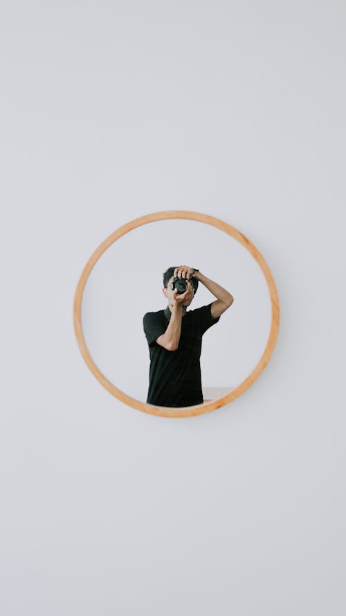 Round Mirror with Image of Man in Black Shirt