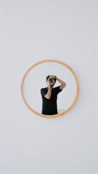 Contemporary minimalist shot of a photographer's reflection in a round wall mirror.