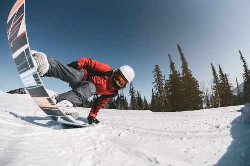 Free Snowboarder in a red jacket cutting through snow on a clear winter day. Stock Photo