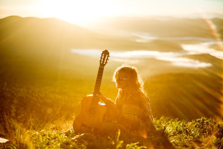 Woman Sitting With Guitar At Sunset