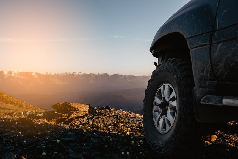 Pickup wheel arch and all-terrain tyre against a sunset ridge, photo by Kirill Lazarev on Pexels