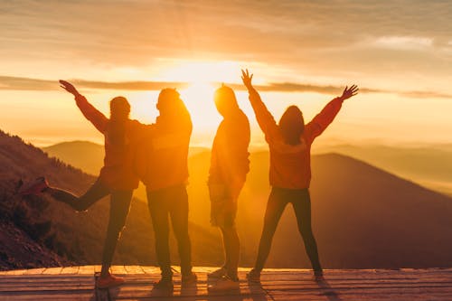 Silhouette of People Standing on Cliff during Sunset