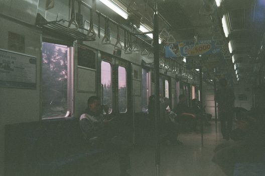 Passengers seated inside a dimly lit train carriage during a journey.
