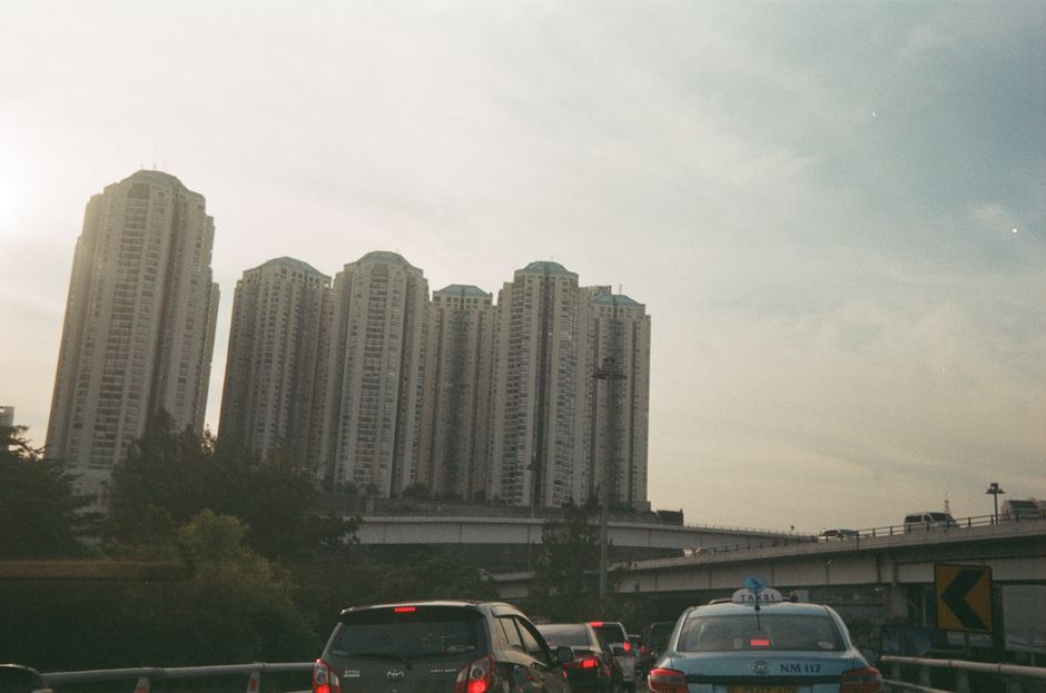 Highrise buildings and traffic captured beneath a cloudy sky in a bustling city.