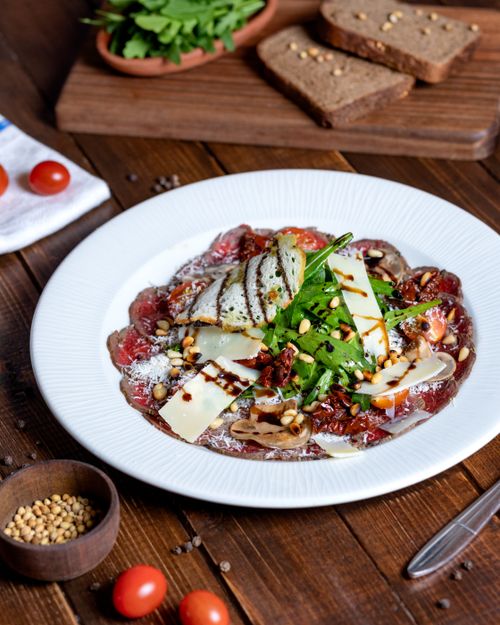 Free Delicious Italian beef carpaccio with shaved cheese, greens, and balsamic glaze. Stock Photo