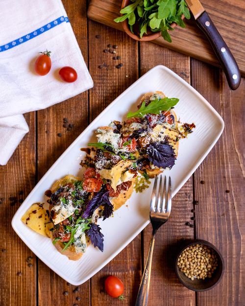 Free Deliciously plated bruschetta garnished with herbs on a wooden table. Stock Photo