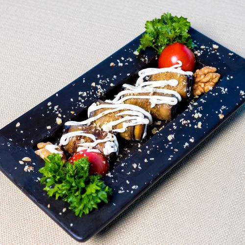 Free Savor this exquisite eggplant dish adorned with fresh tomatoes, parsley, and a drizzle of cream. Stock Photo
