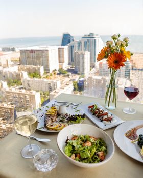 Elegant dining table with seafood and salads overlooking Baku cityscape.