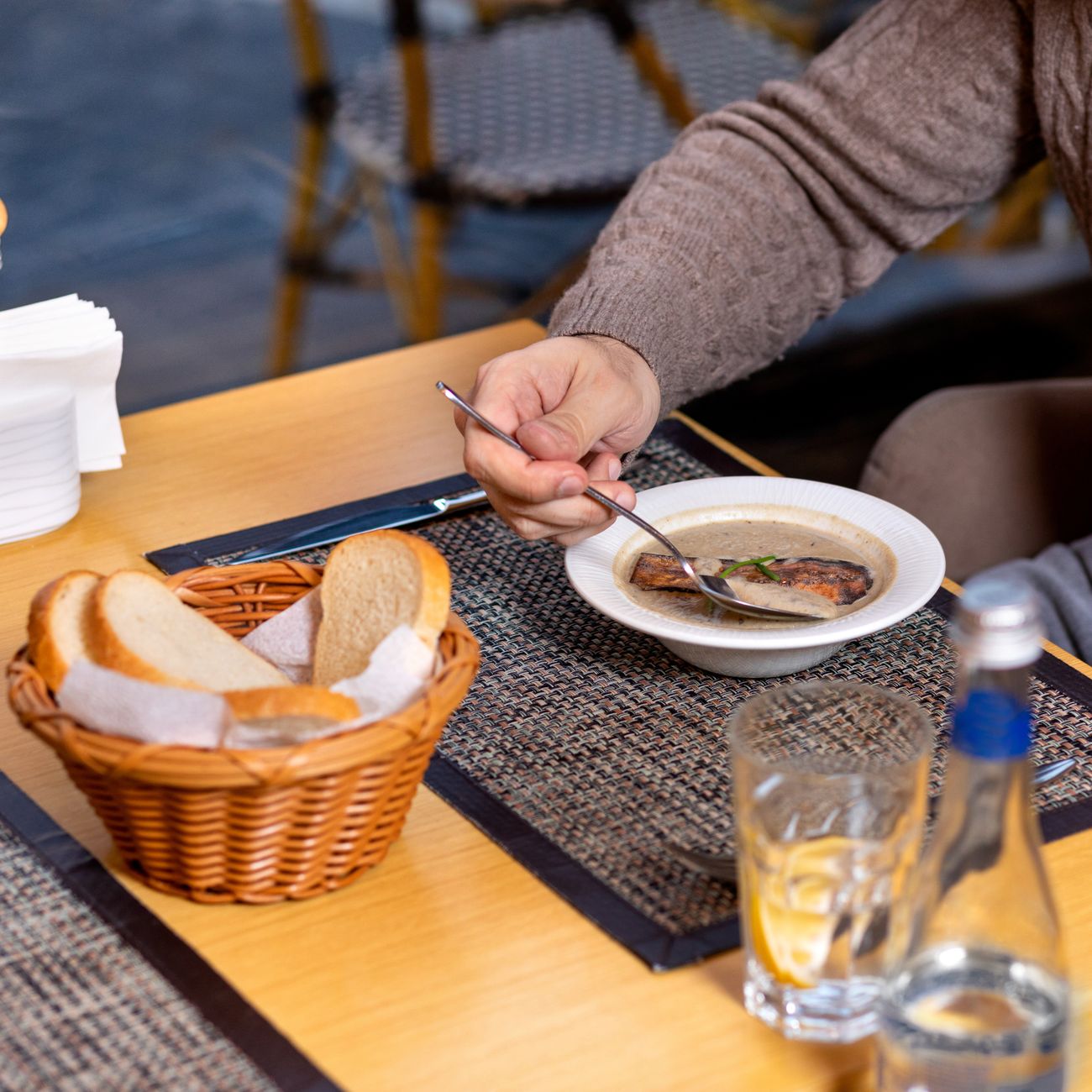 A person enjoying soup with bread in a cozy indoor restaurant setting.