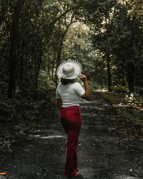 Free Woman in sunhat walking on a forest path, showcasing serenity and style. Stock Photo