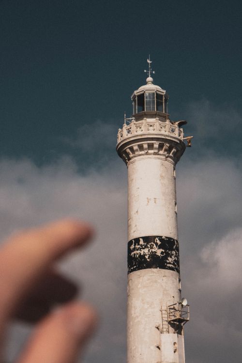 Free Captured at Istanbul's iconic Rumeli Feneri Lighthouse with a foreground hand pointing towards the towering structure. Stock Photo