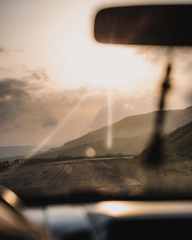Captivating view of a road through hills at sunset, framed from a car interior.