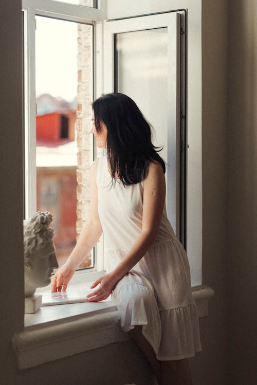 A Woman Sitting on a Window Sill