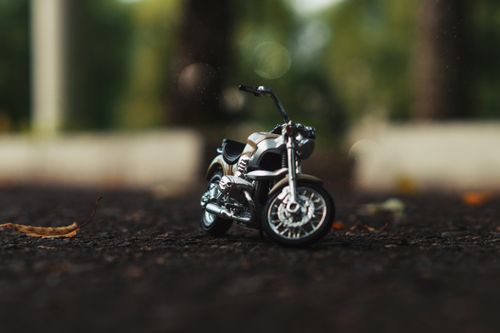 Free A close-up shot of a miniature motorcycle replica on an outdoor surface with blurred background. Stock Photo