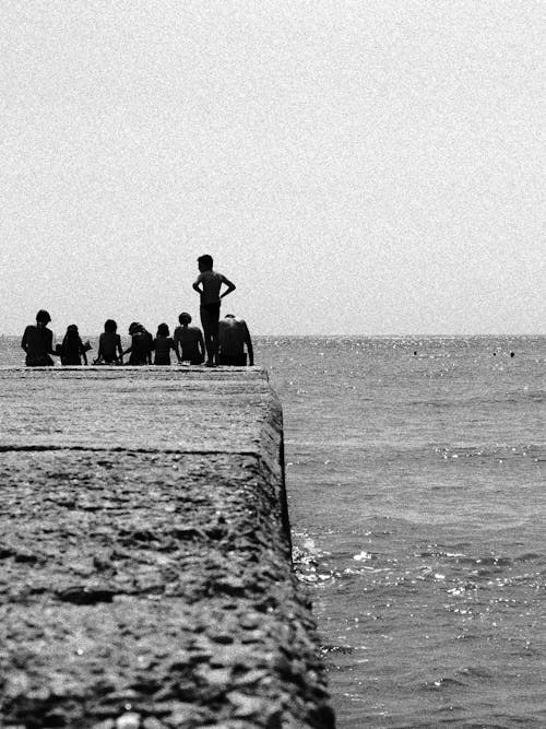 People Sitting on Concrete Dock near Ocean