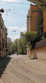 Charming city street scene with tram rails, residential buildings, and green trees.