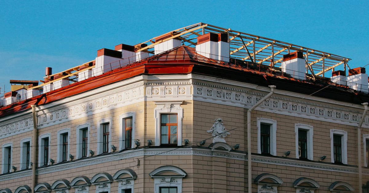 Detailed view of an ornate classical architecture building facade with intricate designs and a red roof.