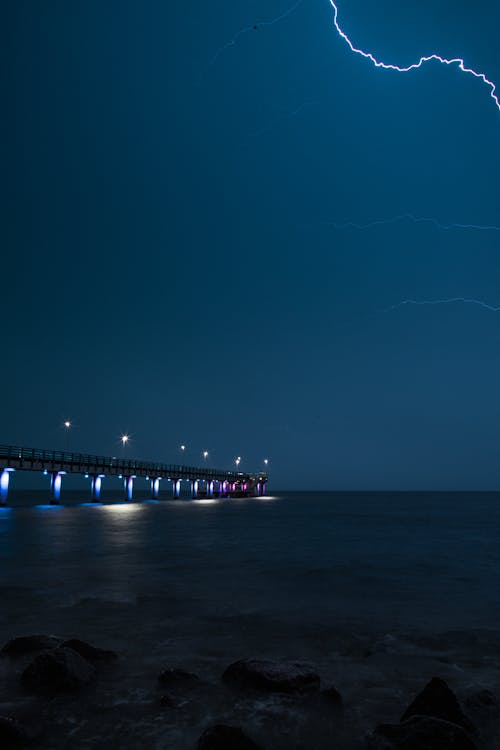 Foto d'estoc gratuïta de cel nocturn, cos d'aigua, llamp