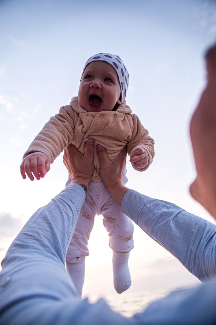 A Person Lifting A Baby