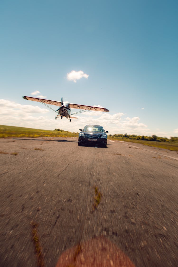 Car And Airplane Flying Over Tarmac