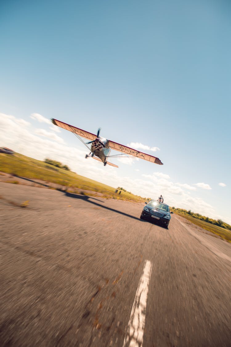 Airplane Flying Over Car On Tarmac