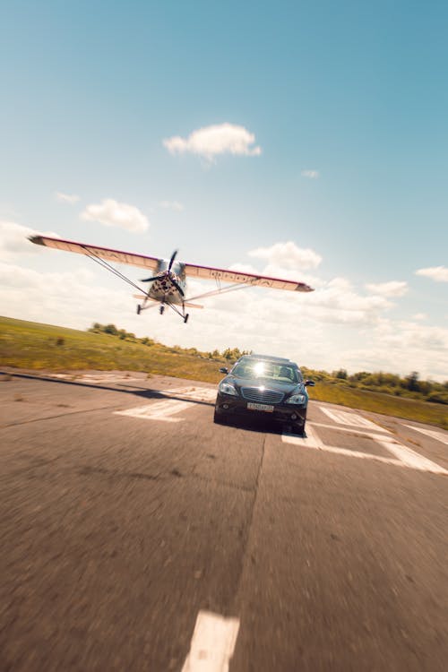 Blurred Motion of a Plane Flying Over a Car on a Track 