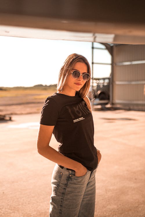 Free Woman in Black Crew Neck T-shirt and Blue Denim Jeans Wearing Black Sunglasses Stock Photo