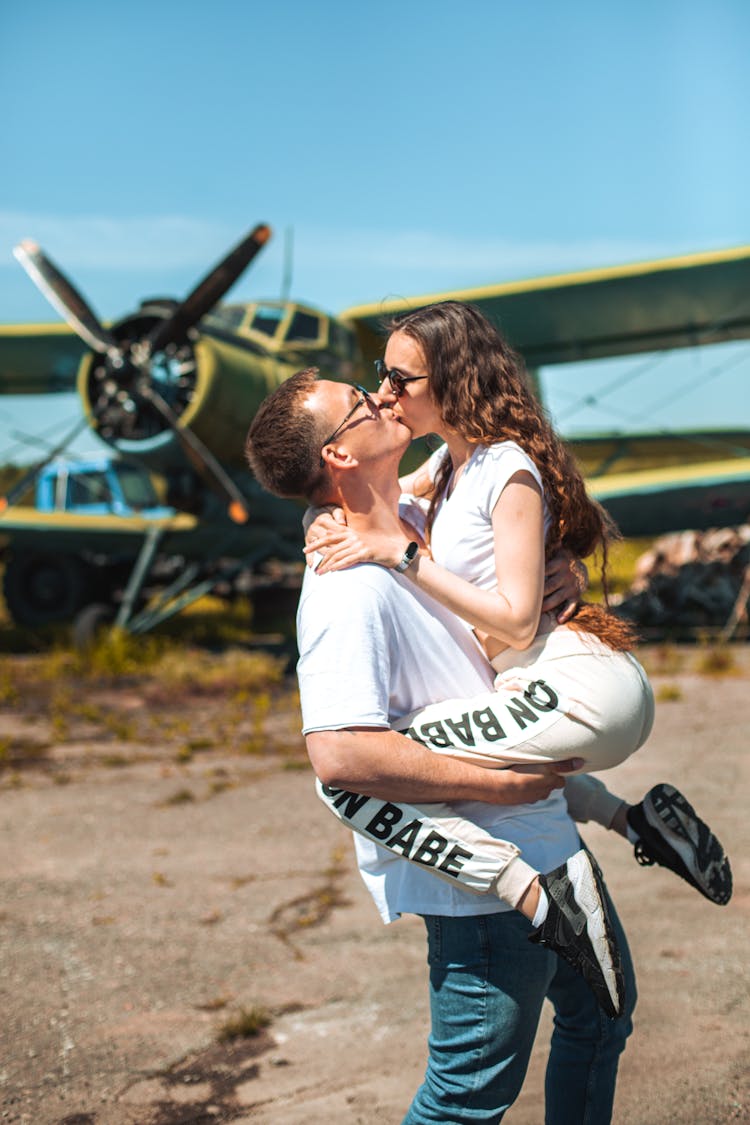 Couple Kissing In Front Of An Airplane 