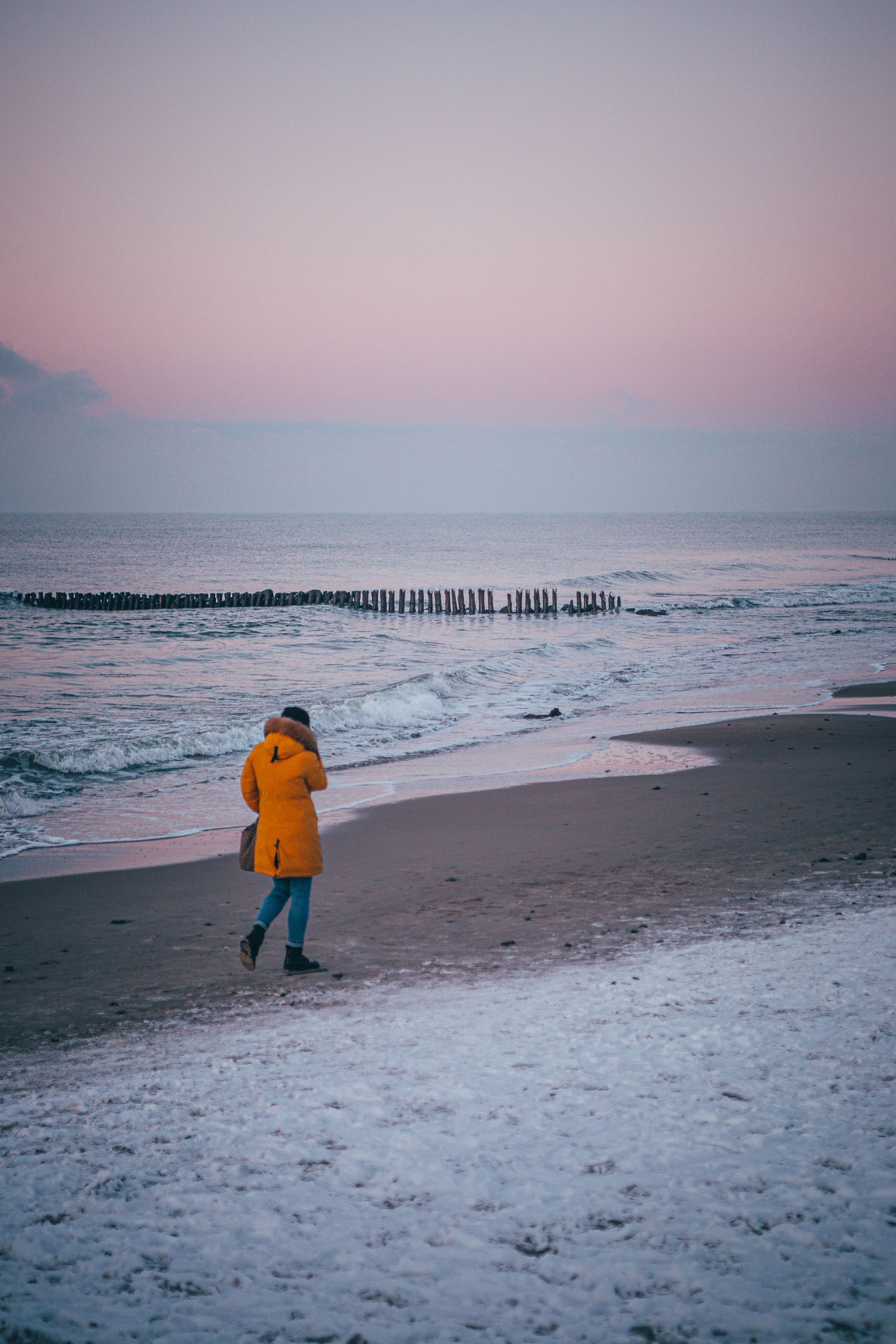 A Person in Yellow Jacket Walking on the Beach · Free Stock Photo