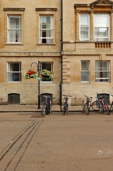 Bicycles lined up outside a classic urban apartment facade with flower boxes.