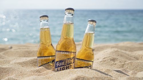 Free Chilled San Mig Light beer bottles on a sunny beach in the Philippines. Stock Photo