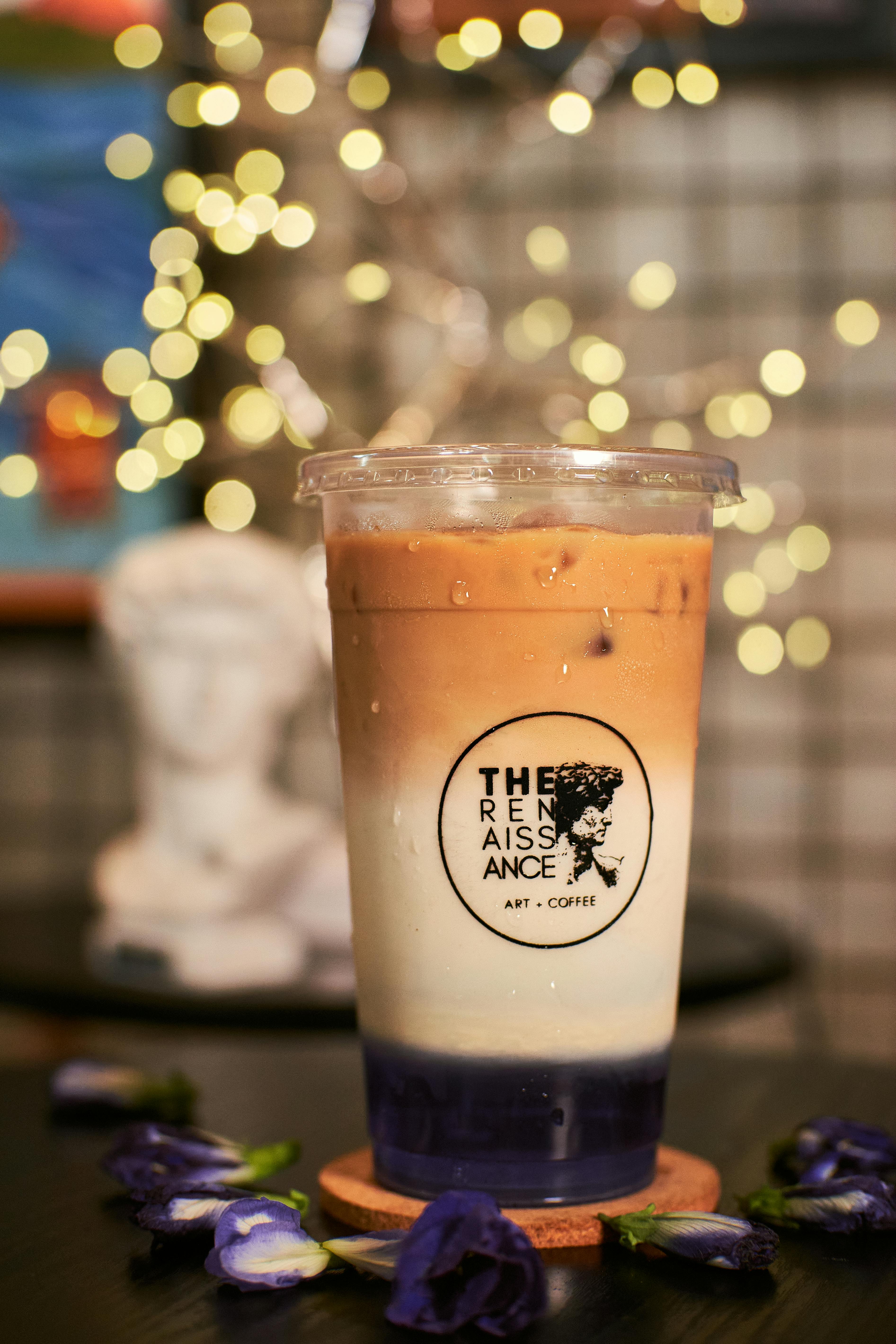 Aesthetic iced coffee exhibited in an art cafe with fairy lights creating a cozy ambiance.