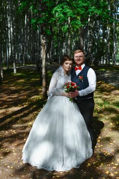 Bride and groom pose together in a sun-dappled forest