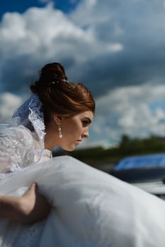 Bride in white wedding gown preparing for her big day under a dramatic sky.