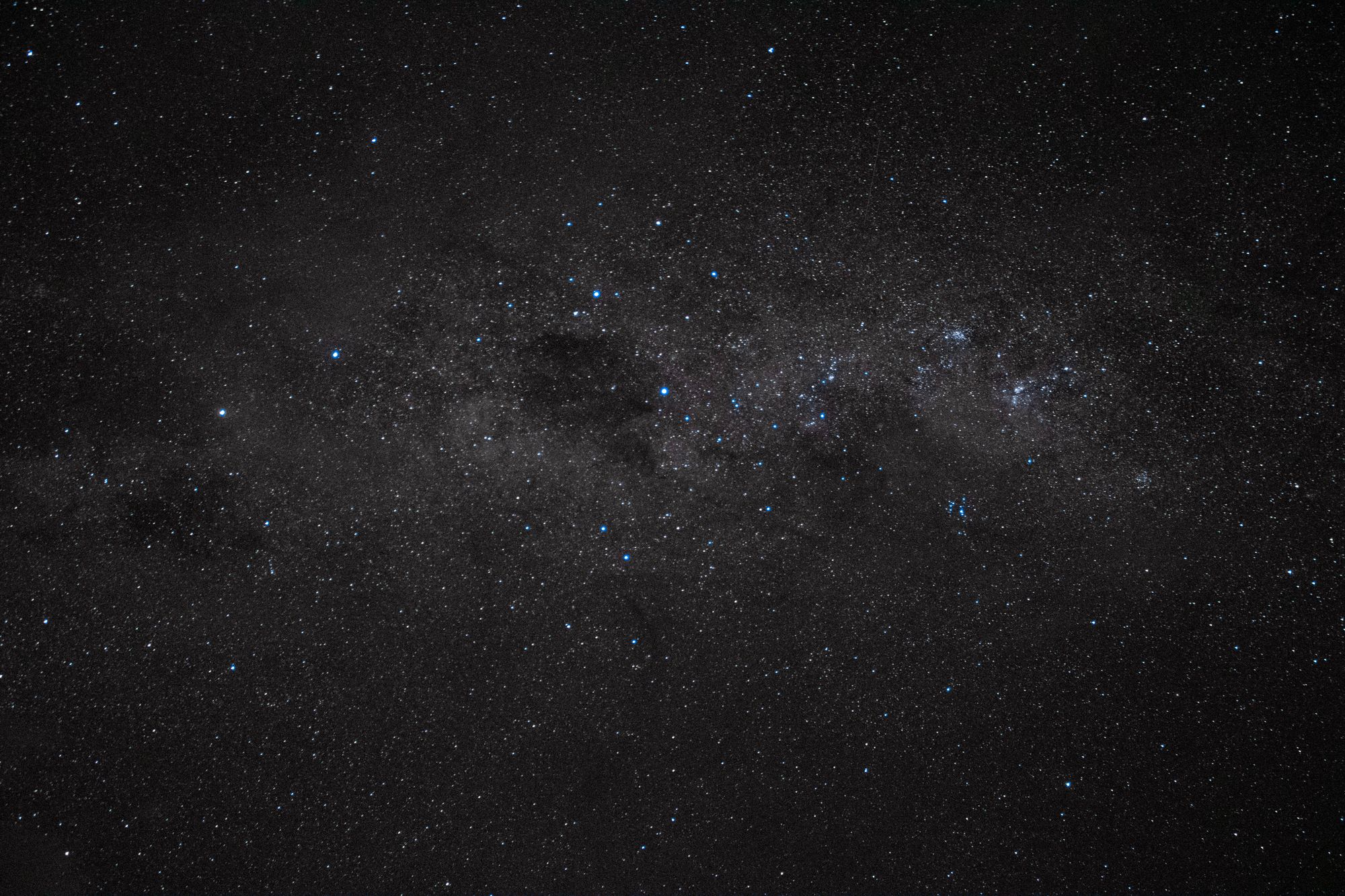 Cielo nocturno estrellado con la Vía Láctea y la constelación del Escorpión sobre un horizonte oscuro