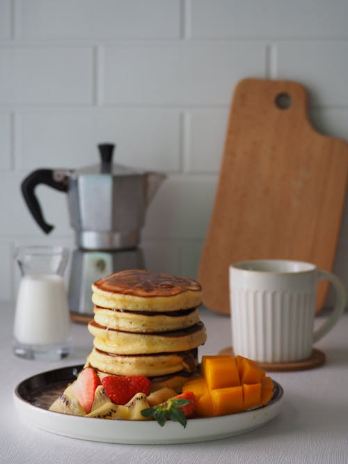 Stacked Pancakes with Fruit Slices on a Plate 