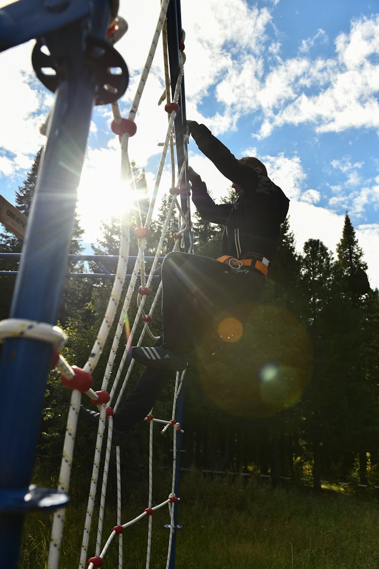 Person In Black Jacket And Black Pants Climbing On A Net