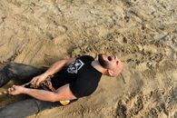 Man in Black Crew Neck T-shirt Lying on Sand and Pulling a Rope