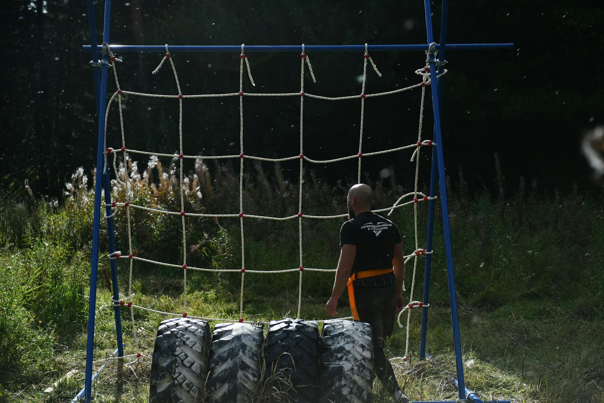 Man in Black T-shirt Standing Beside a Net of an Obstacle Course