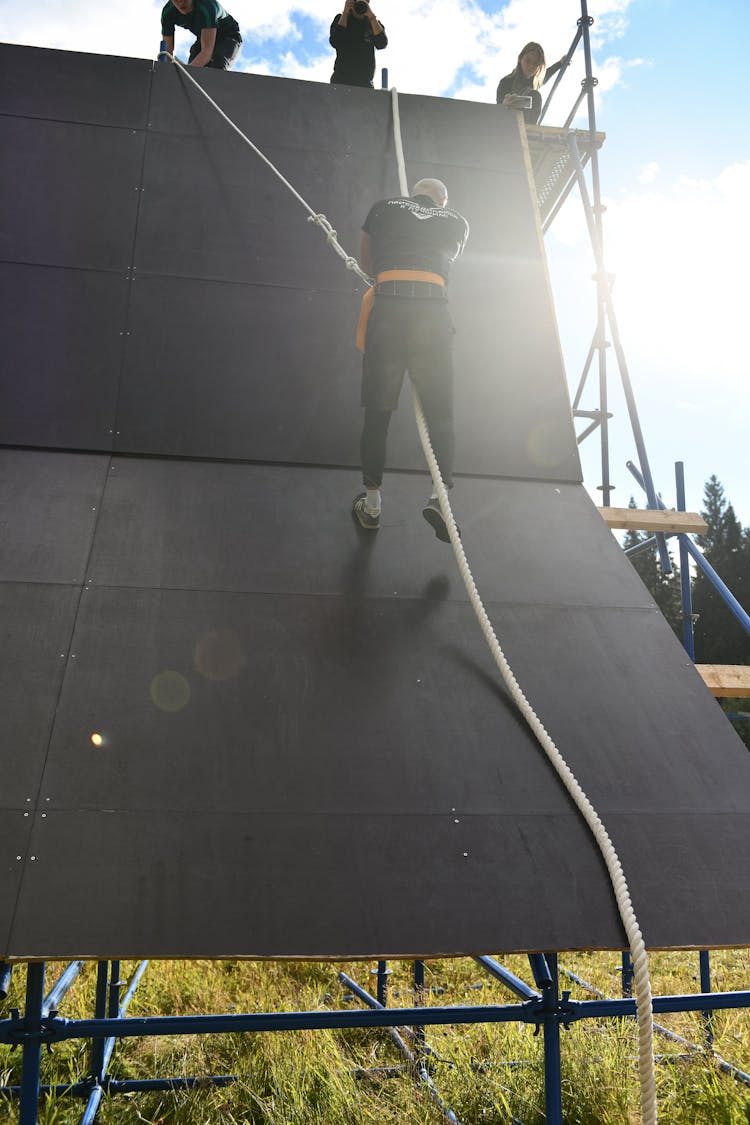 Person Climbing A Wall With A Rope