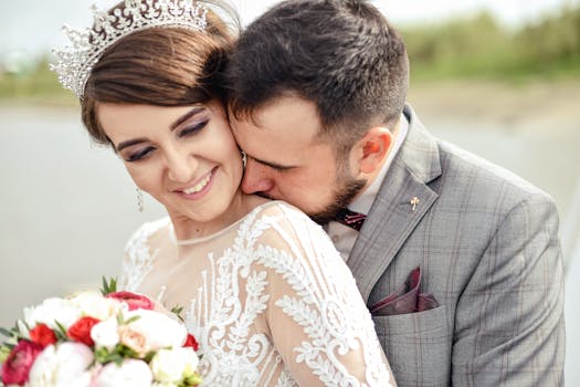 Bride and groom celebrating love outdoors, wearing elegant attire and joyful smiles.