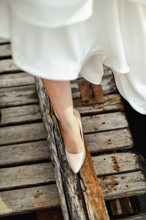 Free A close-up of a bride's elegant soft pink heels on rustic wooden planks, capturing wedding elegance. Stock Photo