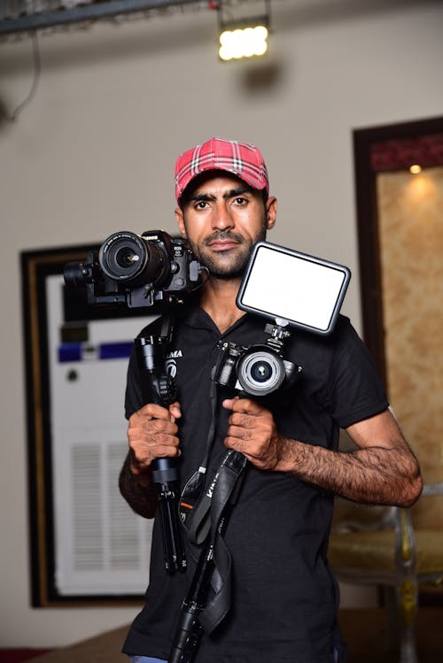 Man in Black Polo Shirt Holding Camera Stands