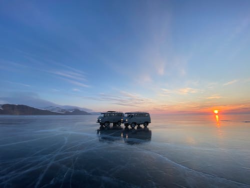 Two Vans Parked on Frozen Lake at Dusk