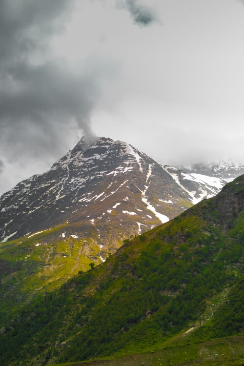 Free Breathtaking view of a snow-capped mountain peak enveloped by clouds, showcasing nature's grandeur. Stock Photo