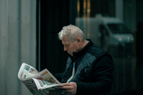 Man in Black Jacket Reading Newspaper