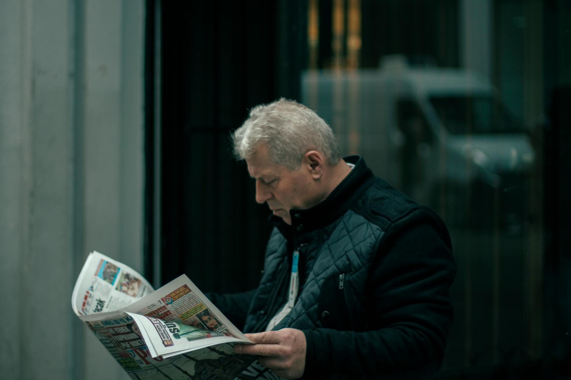 A middle-aged man reads a newspaper in Istanbul, Turkey, reflecting focus and concentration.